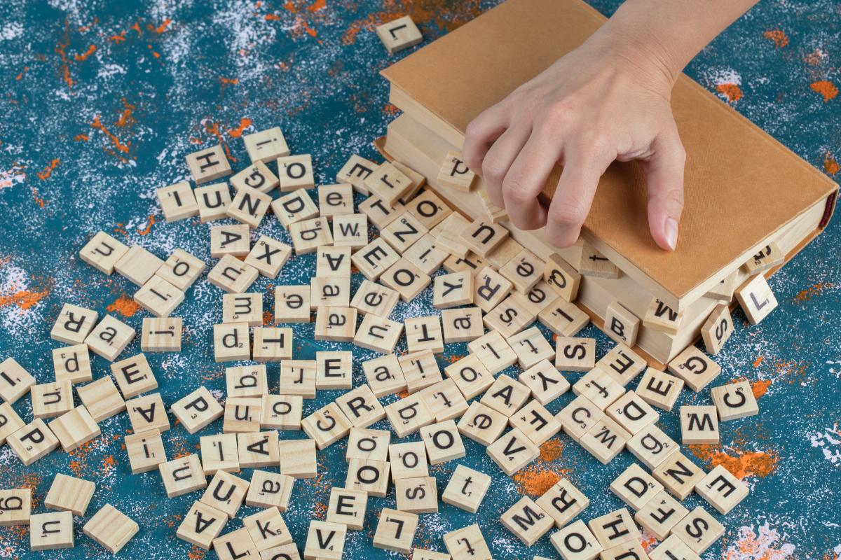 Boite en bois ouverte avec plein de lettres du jeu scrabble autour